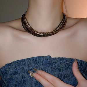 Detail of layered bohemian seed bead choker necklace in bronze and dark brown on model