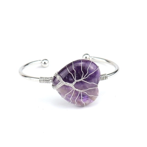 Detailed view of handmade copper wire-wrapped heart amethyst crystal on silver bangle