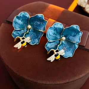 Detail of vintage flower and bee enamel earrings on a classic brown jewelry box
