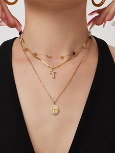 Close-up of layered gold necklaces with cross and Virgin Mary charms on a neck model