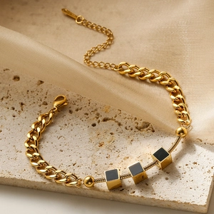 Gold stainless steel link bracelet with shell charms on marble and silk fabric