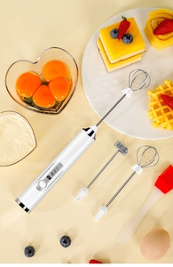 Electric hand mixer set with dual whisk attachments and a red silicone spatula
