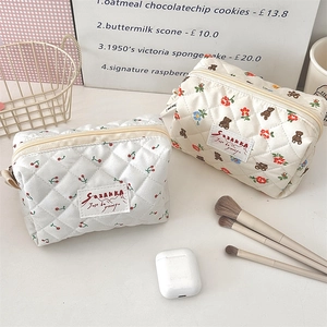 Détail de trousses de maquillage en coton matelassé avec motifs cerises et ours et poignées