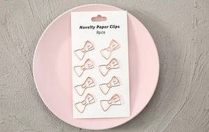 Close-up of 8 pieces rose gold bow-shaped metal paper clips on white card packaging
