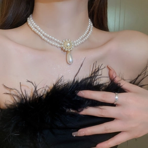 Détail d'un collier de perles à deux rangs avec fermoir soleil doré et pendentif goutte