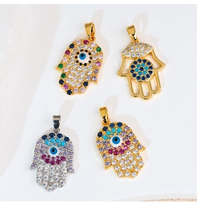 Dettaglio di quattro ciondoli mano di Fatima in oro e argento con zirconi colorati malocchio