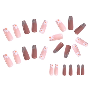Detail view of pink and brown press-on nails with daisy patterns and glitter accents