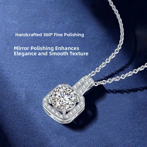 Close-up of silver halo pendant with round moissanite on textured blue fabric background