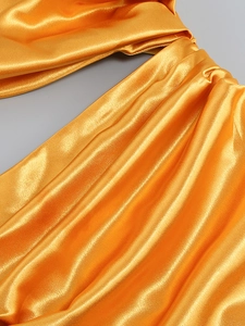Detailed close-up of glossy orange satin fabric with elegant drape and smooth texture