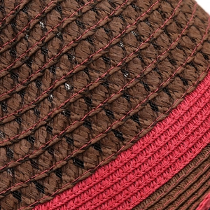 Close-up of hand-woven straw hat detail in dark coffee and bright magenta colors