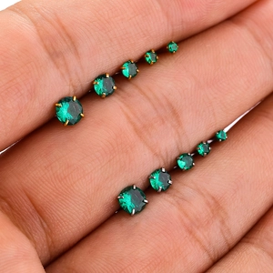 Dettaglio dei piercing con zircone verde in oro e argento sulla mano per misura