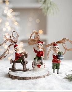 Detailed view of three resin Christmas elf ornaments with gift box and rocking horse