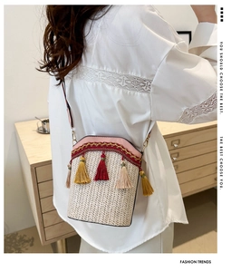 Detail of woven straw bucket bag with colorful tassels and pink patchwork strap