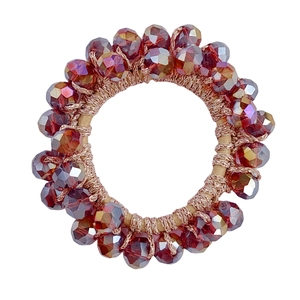 Macro shot of dark red and amber faceted crystal beads on an elastic hair tie