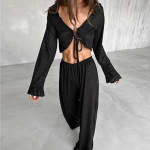 Détail d'un ensemble deux pièces en maille noire avec haut court noué et pantalon large