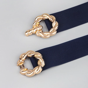 Detail of navy blue elastic waist belt featuring a textured golden twist metal buckle