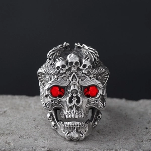 Detailed close-up of gothic skull ring with red gemstone eyes on a textured stone surface