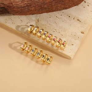 Minimalist gold cross hoop earrings in multiple colors on a natural stone base