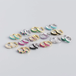 Close-up of gold and silver huggie earrings with colorful rectangular zircon stones