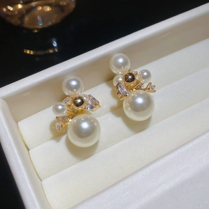 Vue macro de boucles d'oreilles en perles dorées 14 carats et zircons dans un écrin