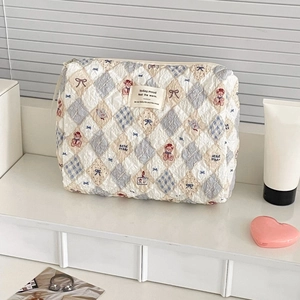 Detail of quilted cosmetic bag featuring cute bear pattern and blue contrast stitch