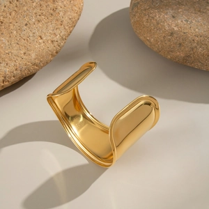 Macro detail of wave-shaped wide cuff bracelet in 18K gold plated stainless steel