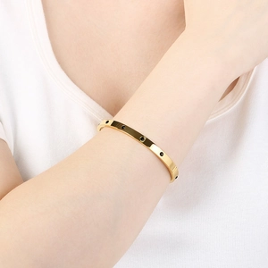 Detail of gold minimalist bangle with black stone inlay worn on a model wrist