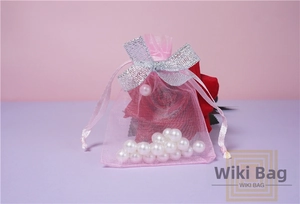 Pink organza drawstring gift bag with silver sequin bow detail and sheer texture