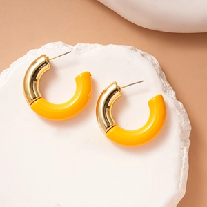 Detail of C-shaped acrylic earrings with gold-toned metal and yellow resin finish