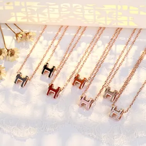 Close-up of multicolored H-shaped enamel pendants with rose gold chains in a luxury layout