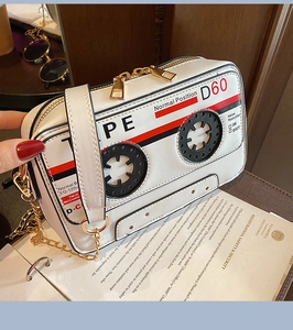Macro shot of white cassette-shaped crossbody bag with gold chain and vintage radio design