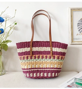 Detail of colorful striped straw bag with brown leather handles on a grey sofa