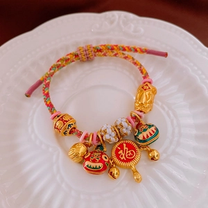 Détail du bracelet tressé porte-bonheur avec charmes plaqués or et pendentifs lion chinois