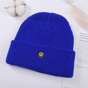 Primer plano de un gorro de punto azul brillante con bordado de cara sonriente amarilla