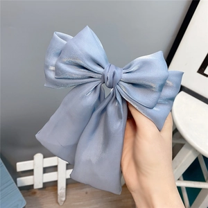 Close-up of light blue triple-layered bow hair clip with flowing long ribbons