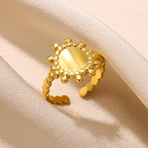 Detail view of gold stainless steel sunburst ring on elegant beige silk fabric background