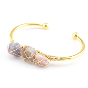 Detail of handcrafted gold wire wrapped cuff bracelet with purple and pink raw crystals