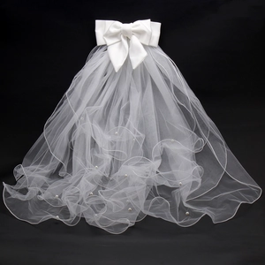 Detail of white bridal veil featuring a large bow and scattered pearls on mesh fabric
