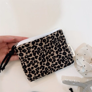 Close-up of leopard print mini pouch with white zipper and a woven black puller detail