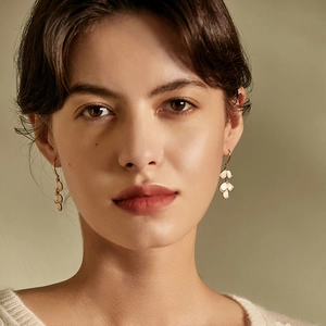 Elegant gold leaf earrings with cat eye stones and diamonds on a stylish model