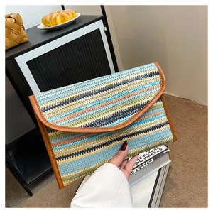 Detail of colorful striped woven envelope clutch with brown leather trim held by a person