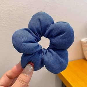 Detail of a large denim blue 3D flower scrunchie with soft cotton twill texture