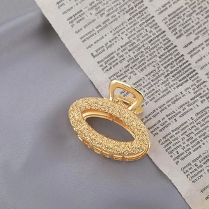 Detail shot of vintage gold metal hair claw clip with oval hollow pattern on text background