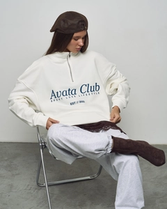 Close-up of white oversized sweatshirt with navy Avata Club letter print and half-zipper