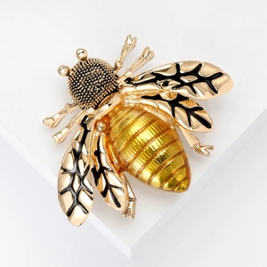 Elegant gold-tone bee brooch with black enamel wing details on white background
