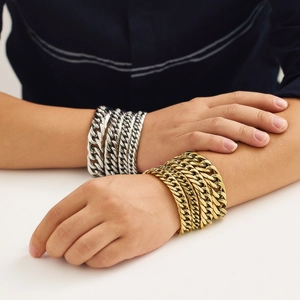 Dettaglio di bracciali a catena cubana hip hop in oro e argento sui polsi maschili