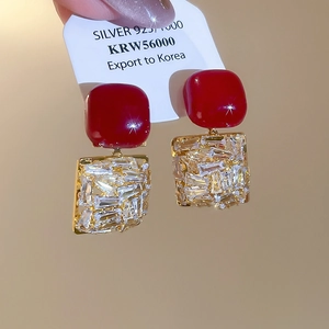 Détail de boucles d'oreilles dorées avec pierres rouges et zircons sur base en argent 925