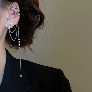 Gros plan d'un ear cuff double cœur avec chaînes argentées et détails de perles blanches