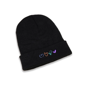 Détail du bonnet en maille noire orné de quatre broderies en forme de cœur coloré