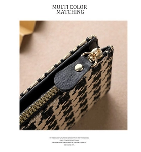 Detailed macro of houndstock fabric, black leather trim, and golden zipper of small wallet